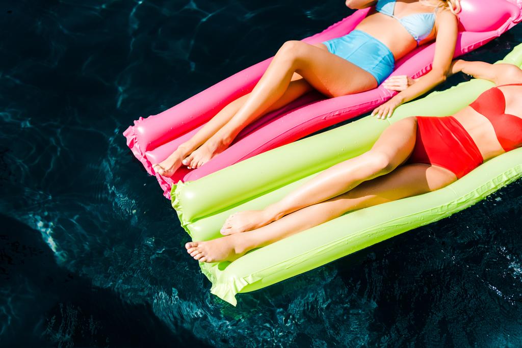 vista cortada de meninas tomando banho de sol em colchões infláveis na piscina
 - Foto, Imagem