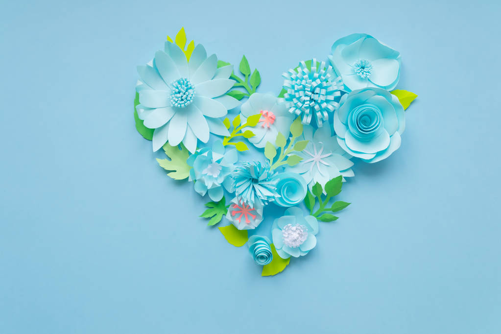 Серце з квітів синього паперу з зеленим листям на синьому фоні. Вирізати з паперу
. - Фото, зображення