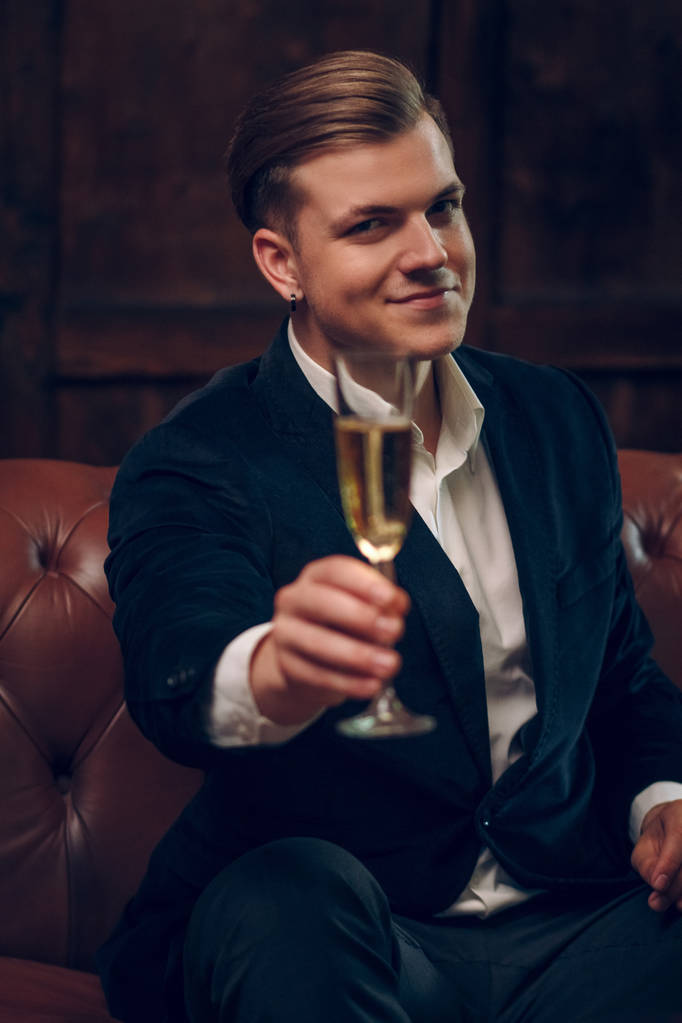 スーツの非常にハンサムな男は、シャンパンのグラスを発生させます - 写真・画像