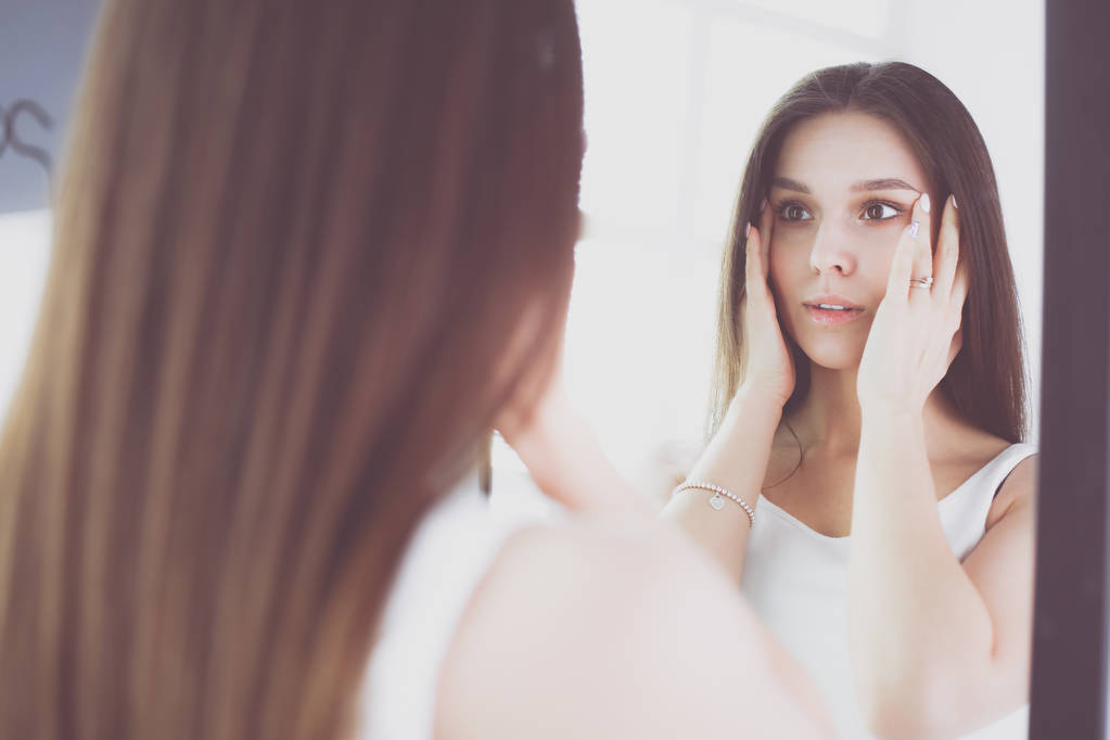 Jovem mulher olhando-se reflexão no espelho em casa
. - Foto, Imagem
