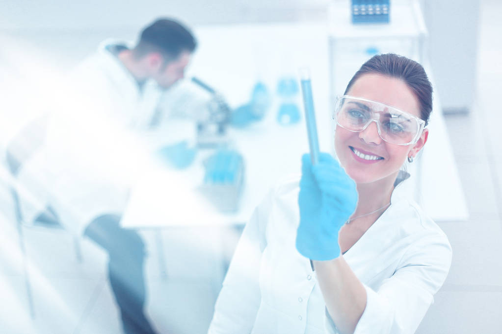 mujer científica sonriente mirando el tubo con los resultados del análisis
 - Foto, Imagen