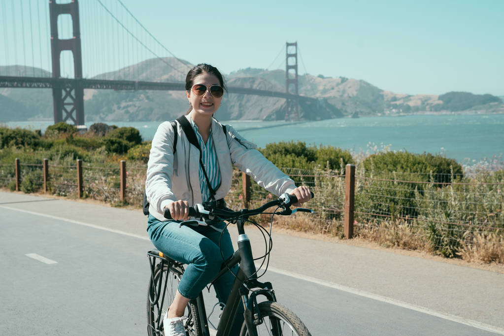 donna asiatica rilassante e godendo il sole in sella gita in bicicletta nella campagna di San Francisco California USA. giovane viaggiatore ragazza visita ponte cancello d'oro lungo la costa in estate
. - Foto, immagini
