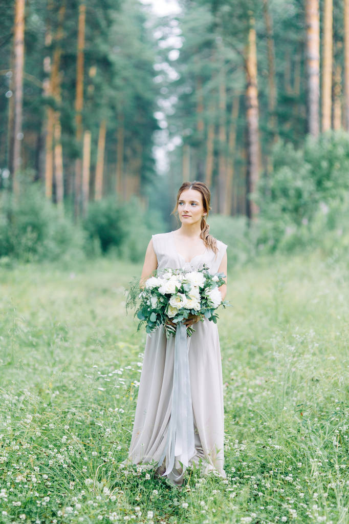 Boudoir photo shoot of the bride in the woods with a bouquet. Flying dress and beautiful girl in the Park. - Foto, afbeelding
