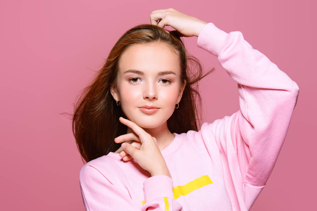 Tini stílus. Gyönyörű fiatal modell jelentő stúdió farmer és rózsaszín pulóver, hosszú haj. Szépség, divat.  - Fotó, kép