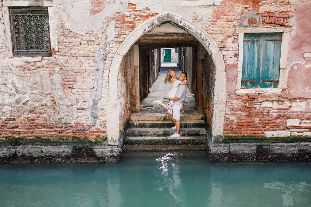 Mooie jonge koppel meisje in jurk man op wit overhemd wandeling door de straten van Venetië Italië - Foto, afbeelding