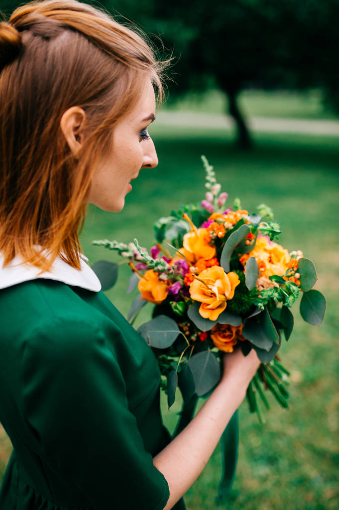 joven mujer de pelo rojo en vestido verde con ramo de flores de verano
 - Foto, Imagen