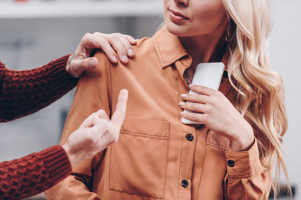 Schnappschuss eines Mannes, der mit dem Finger auf junge Frau zeigt, die Smartphone in der Hand hält, misstraut Konzept - Foto, Bild
