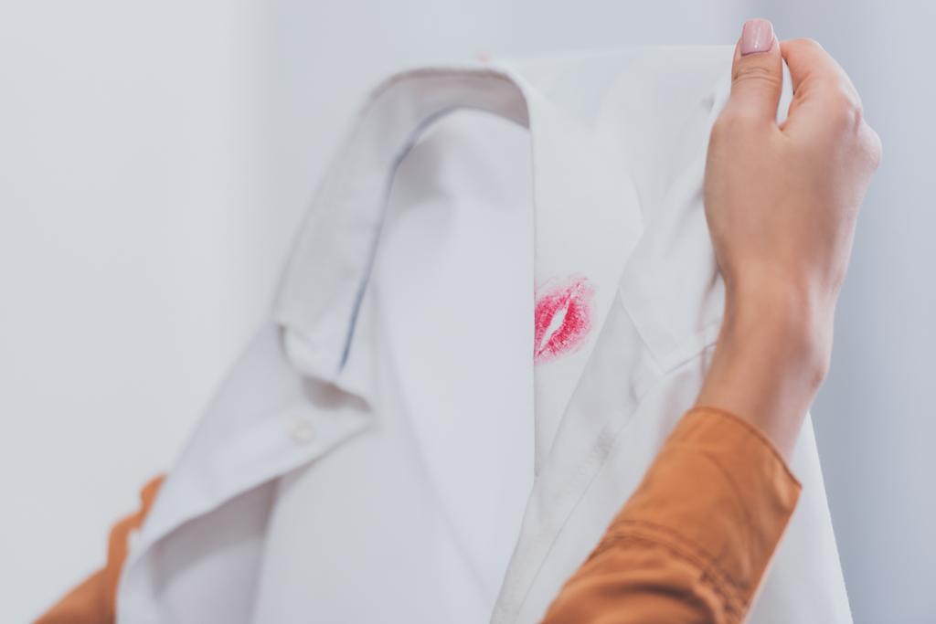 gros plan vue partielle de fille tenant chemise masculine blanche avec traces de rouge à lèvres, concept de trahison
  - Photo, image