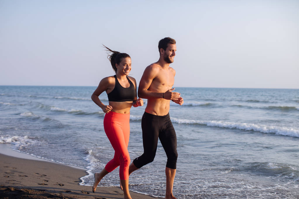 ハンサムな白人男性と美しい女性の砂浜ビーチを走る. - 写真・画像