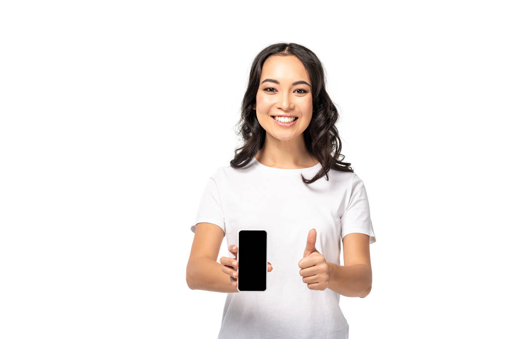 Sorrindo asiático menina segurando smartphone com tela em branco e mostrando polegar para cima isolado no branco
 - Foto, Imagem
