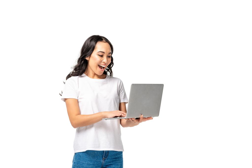 Fiatal ázsiai nő használ laptop és emelése ököl elszigetelt fehér nevetve - Fotó, kép