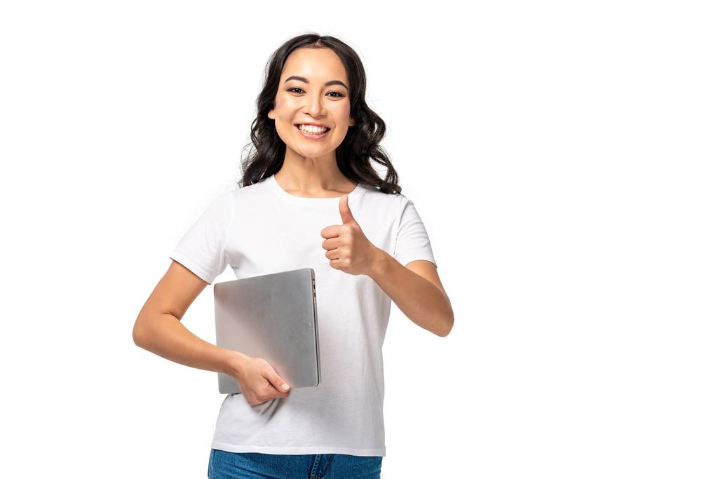 souriant asiatique femme en blanc t-shirt et bleu jeans tenant ordinateur portable et montrant pouce vers le haut isolé sur blanc
 - Photo, image