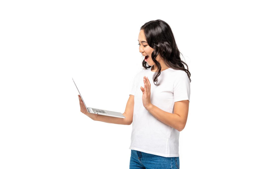 Усміхнена молода азіатка використовує ноутбук і показує жест привітання ізольовано на білому
 - Фото, зображення