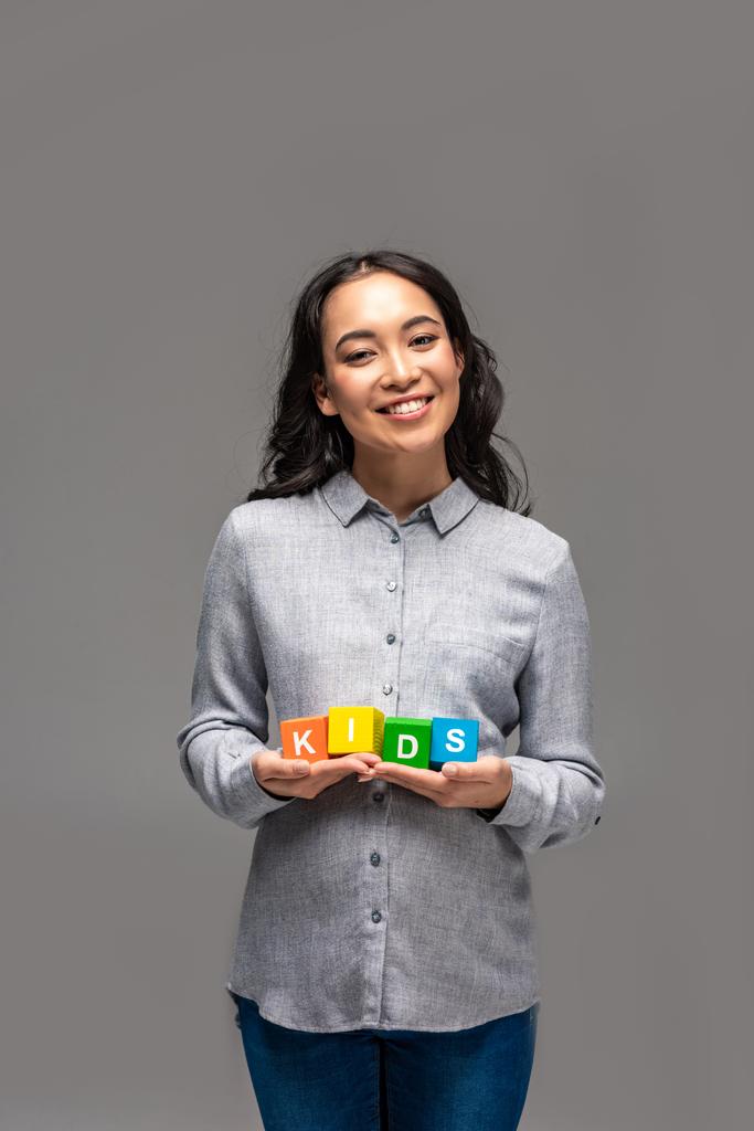 szczęśliwy w ciąży młoda kobieta azjatyckich trzymając alfabet kostki z dzieci słowo na szarym tle - Zdjęcie, obraz