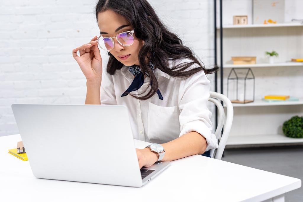Przemyślane freelancer azjatyckich za pomocą laptopa w miejscu pracy do domu i korygowanie okulary - Zdjęcie, obraz