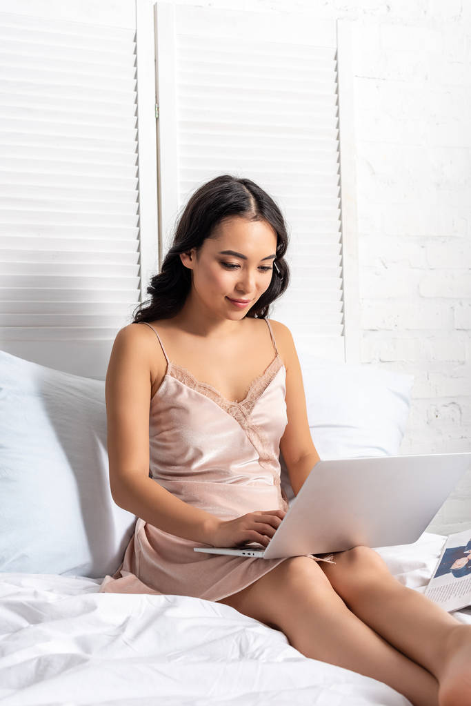 Joven asiático freelancer utilizando el ordenador portátil mientras se queda en la cama
 - Foto, imagen