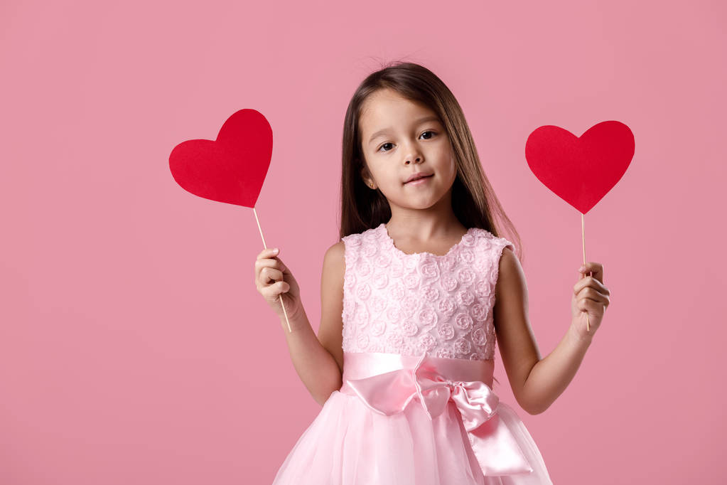 schattig klein meisje in een roze jurk houden een papier-hart - Foto, afbeelding