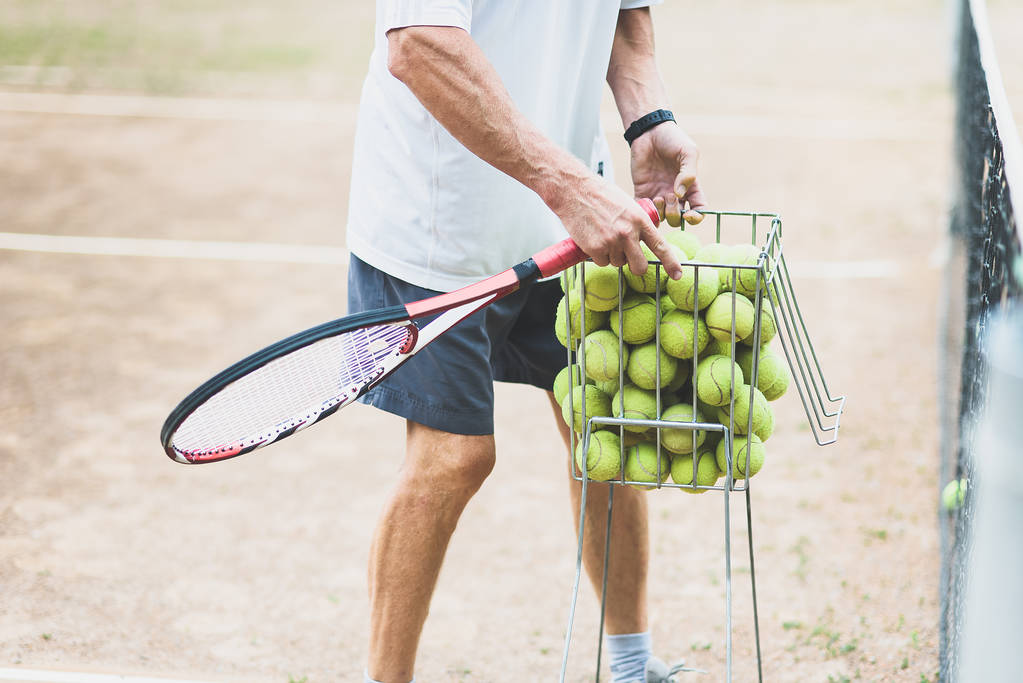coach collecting tennis balls in basket after training, Tennis lesson concept  - Photo, Image