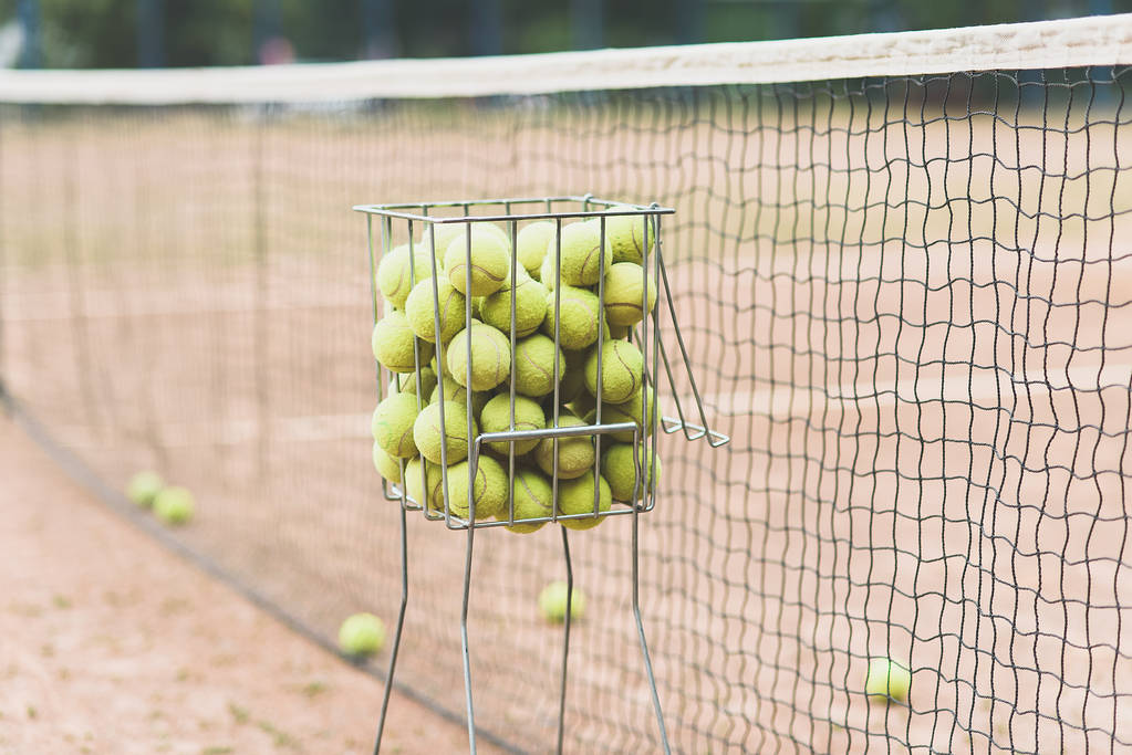 Palle da tennis nel cestino sullo sfondo del campo da tennis
  - Foto, immagini