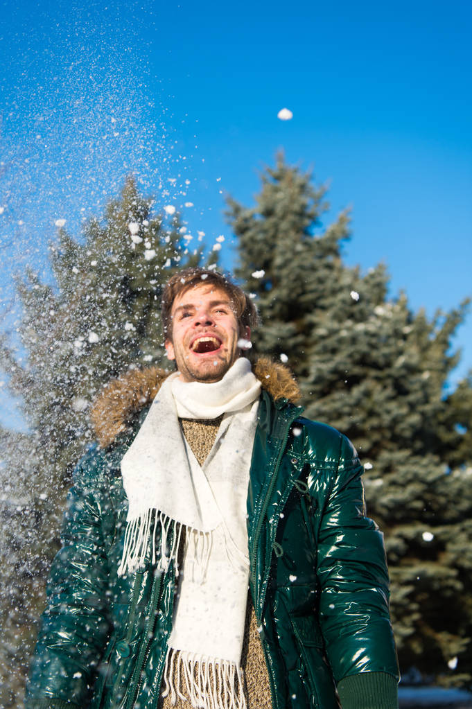 Хлопець насолоджується сонячним зимовим днем. Хіпстер ходить сніжним зимовим днем. Сніжинки в повітрі в яскравий зимовий день. Концепція зимової моди. Чоловік незахищений носити теплий піджак з хутром і шарфом засніжений фон природи
 - Фото, зображення