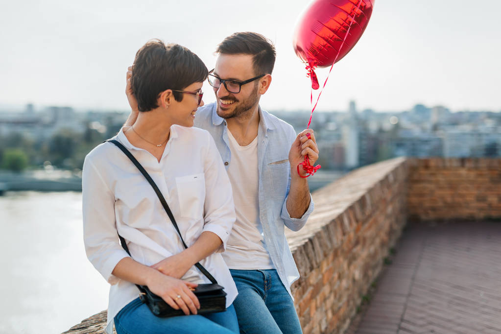Jong koppel in liefde dating en glimlachend buiten terwijl hart baloons - Foto, afbeelding
