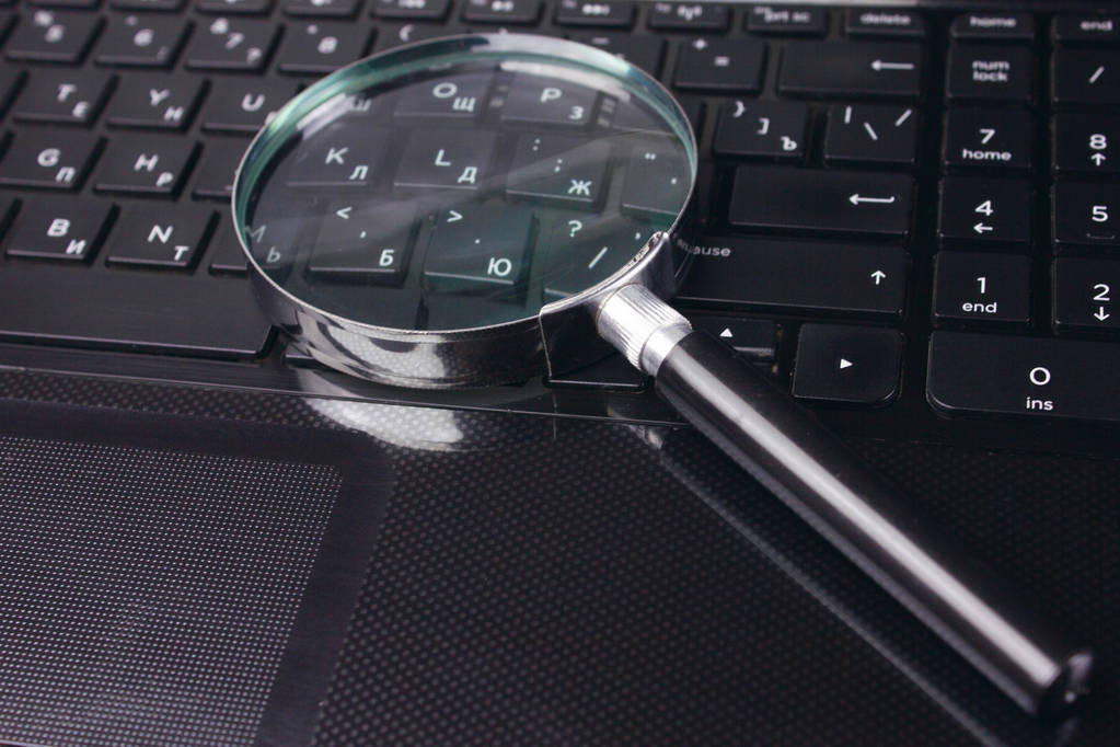 Magnifying glass on black keyboard - Photo, Image
