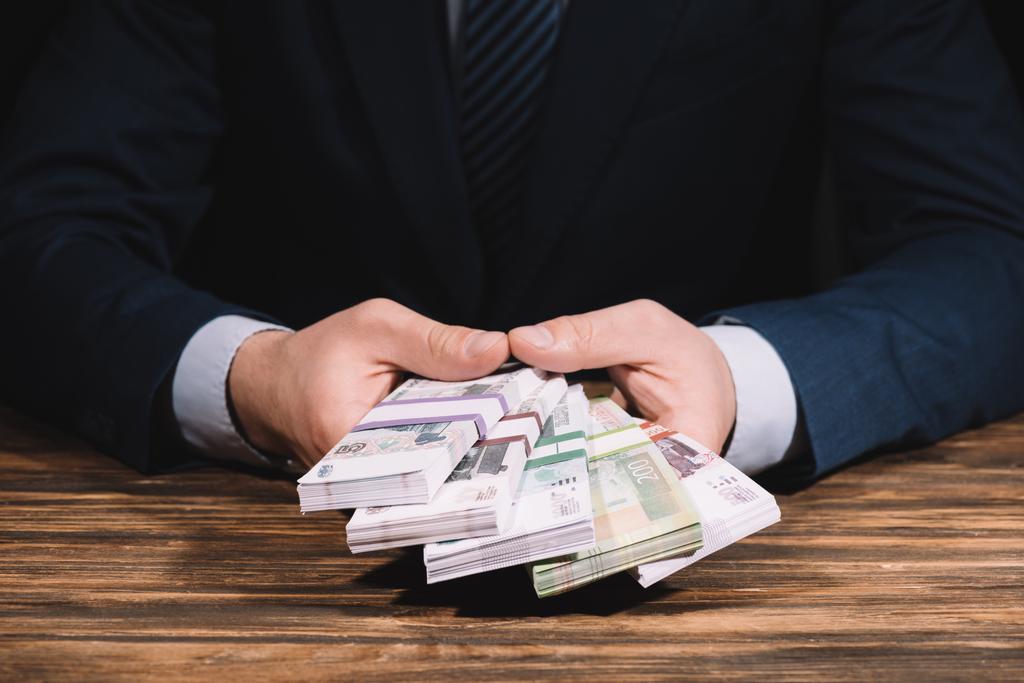 Oříznout záběr podnikatel držení ruských rublů bankovek nad dřevěný stůl      - Fotografie, Obrázek