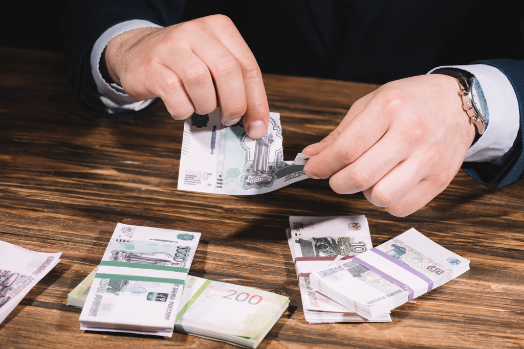 cropped shot of businessman ripping banknote above wooden table with russian rubles  - Photo, Image