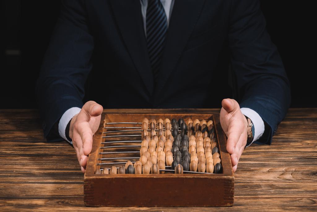 cropped shot of businessman holding counting frame while sitting at wooden table - Photo, Image