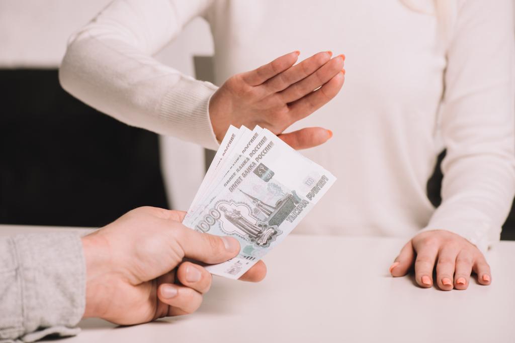 plan recadré de l'homme donnant des billets de banque roubles à la femme gesticulant aucun signe
 - Photo, image