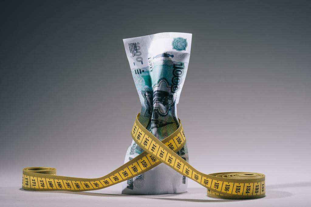 banconota da rubli russi con nastro di misurazione sul concetto grigio di crisi finanziaria
 - Foto, immagini