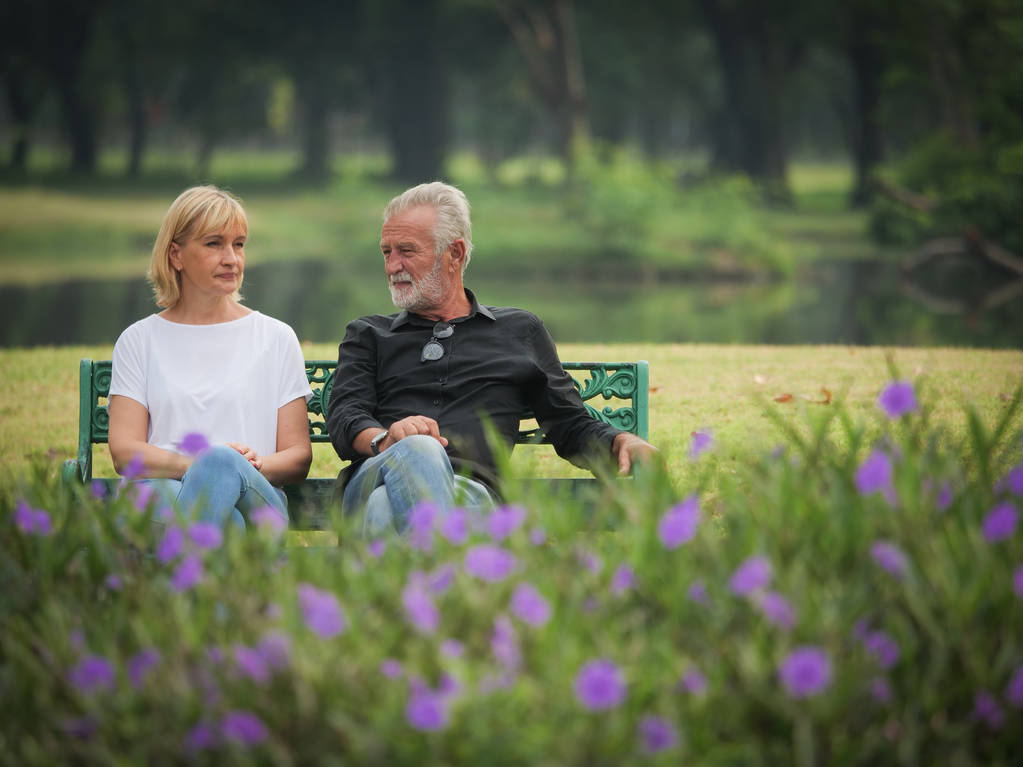 Δύο ευτυχείς τους πρεσβυτέρους συνταξιοδότηση άνδρα και γυναίκας καθισμένος και να μιλήσει στο πάρκο - Φωτογραφία, εικόνα