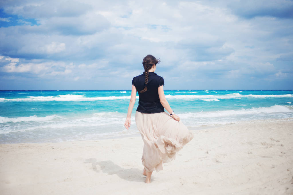 Takaisin näkymä nuori nainen pitkä hame kävely meressä
.  - Valokuva, kuva