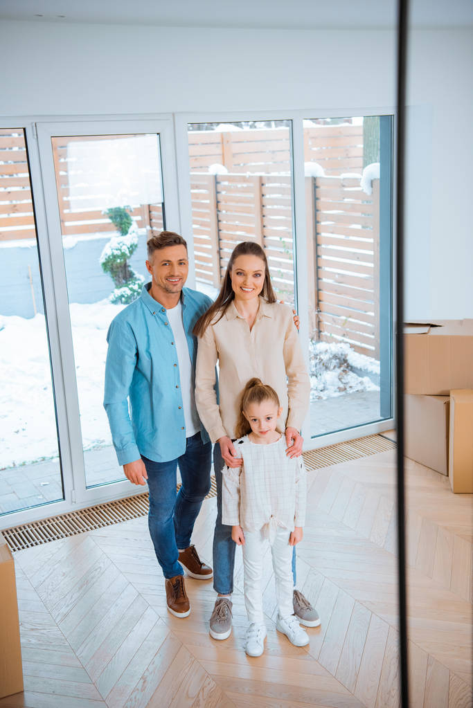 glückliche Eheleute stehen neben süßer Tochter im neuen Zuhause - Foto, Bild