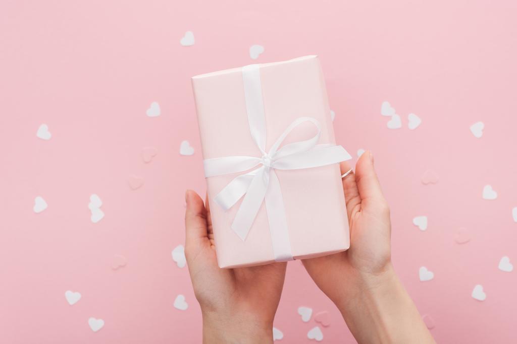 περικοπεί προβολή της γυναίκας κρατώντας δώρο κουτί και χαρτί απομονώνονται σε ροζ καρδιές - Φωτογραφία, εικόνα