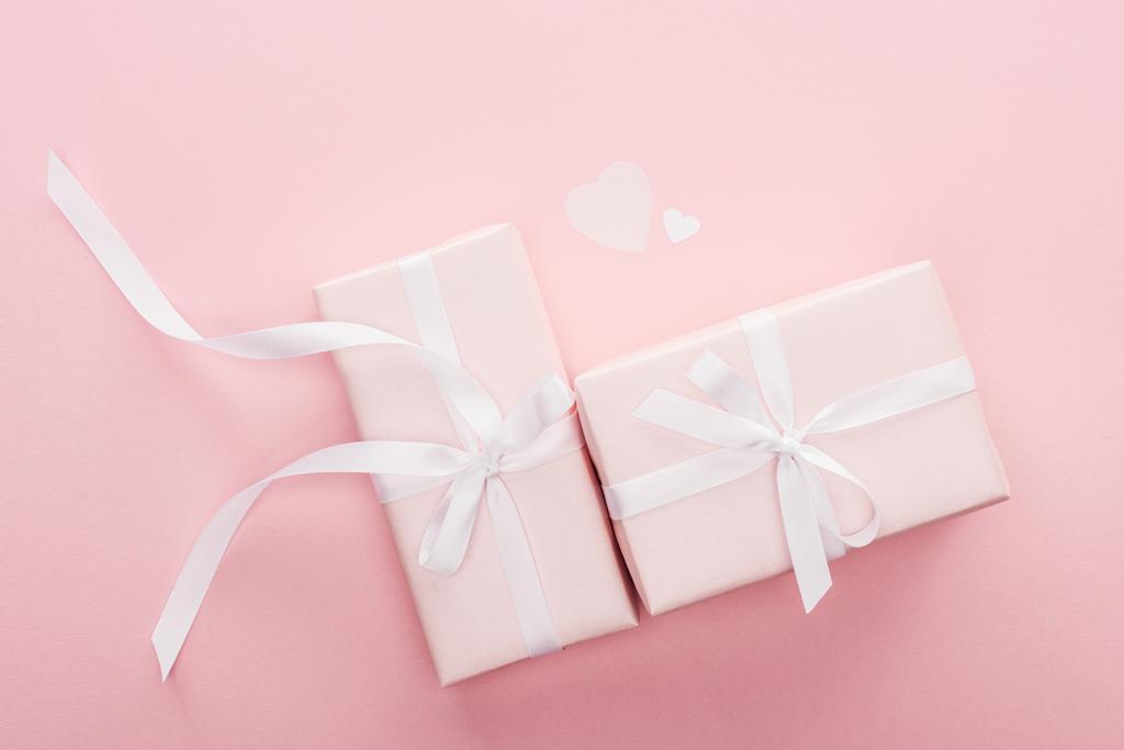top view of gift boxes with ribbons and paper hearts isolated on pink - Photo, Image
