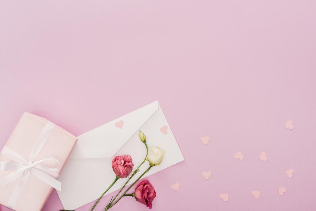 bovenaanzicht van de envelop, doos van de gift, bloemen en papier harten geïsoleerd op roze - Foto, afbeelding
