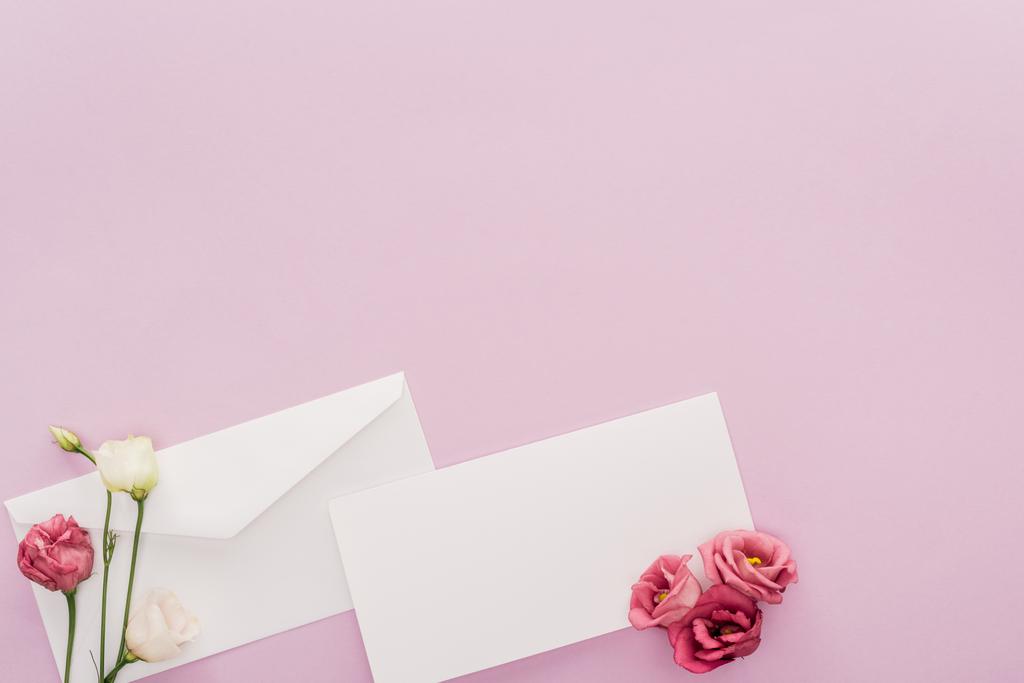 το top view κενή κάρτα, φάκελος και λουλούδια που απομονώνονται σε ροζ με αντίγραφο χώρου - Φωτογραφία, εικόνα