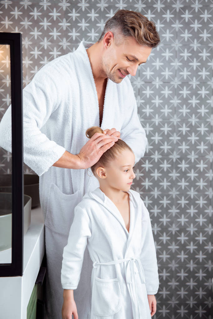 pai feliz fazendo o cabelo da filha bonito de pé no banheiro
  - Foto, Imagem