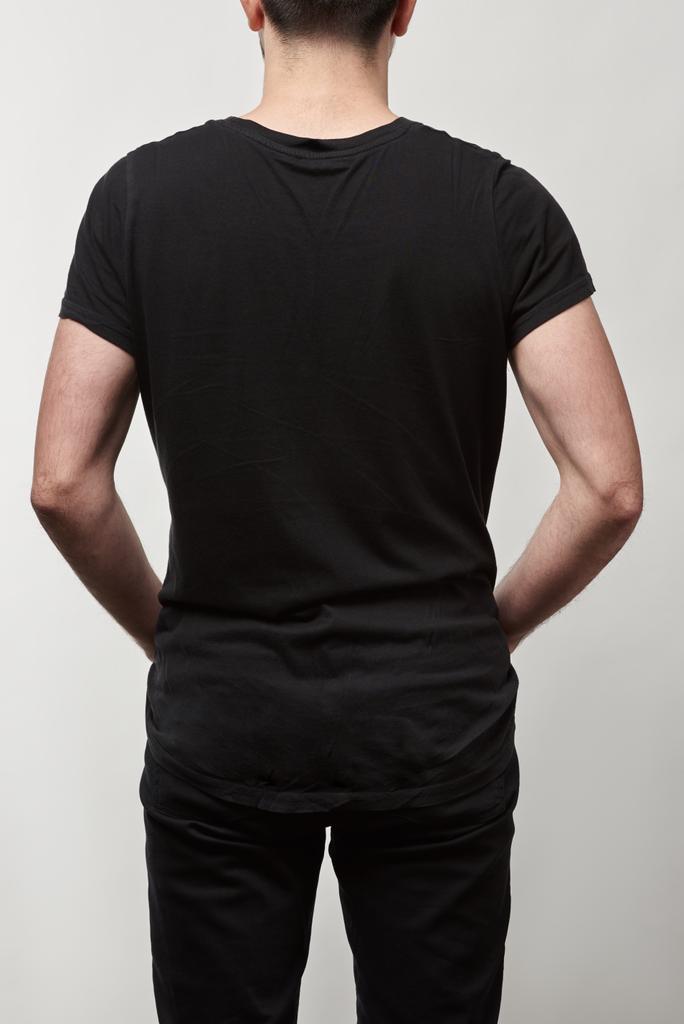πίσω όψη του ανθρώπου σε μαύρο t-shirt με χώρο αντίγραφο που απομονώνονται σε γκρι - Φωτογραφία, εικόνα