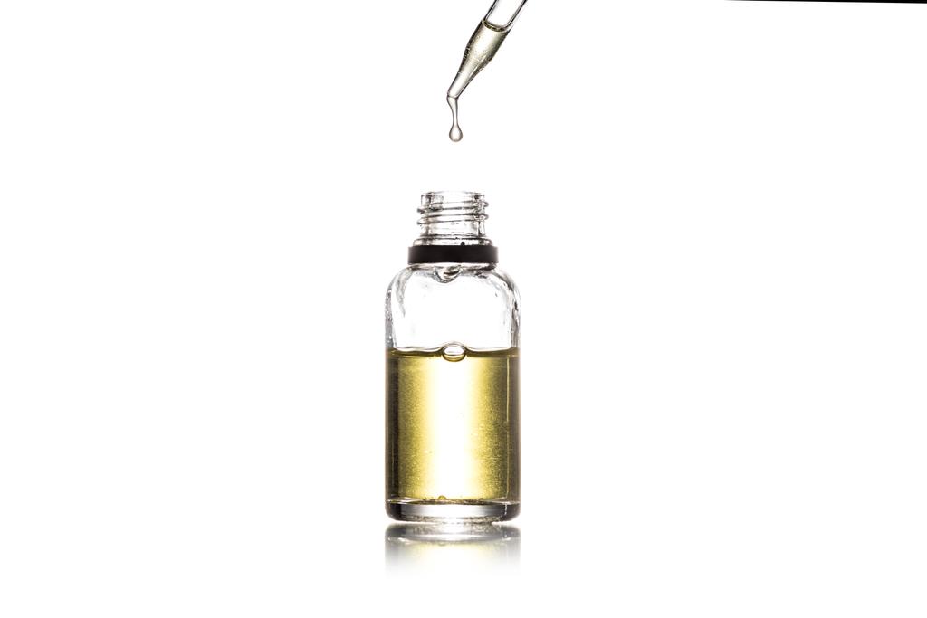 Estudio plano de botella de vidrio con líquido dorado y gotero aislado en blanco
 - Foto, Imagen