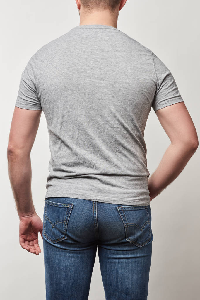 vista trasera del hombre en mezclilla y camiseta con espacio de copia aislado en gris
 - Foto, Imagen