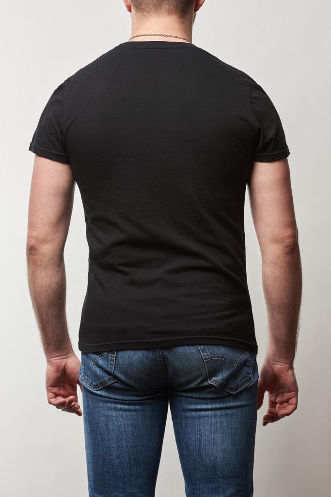 vista trasera del hombre en mezclilla y camiseta negra con espacio de copia aislado en gris
 - Foto, Imagen