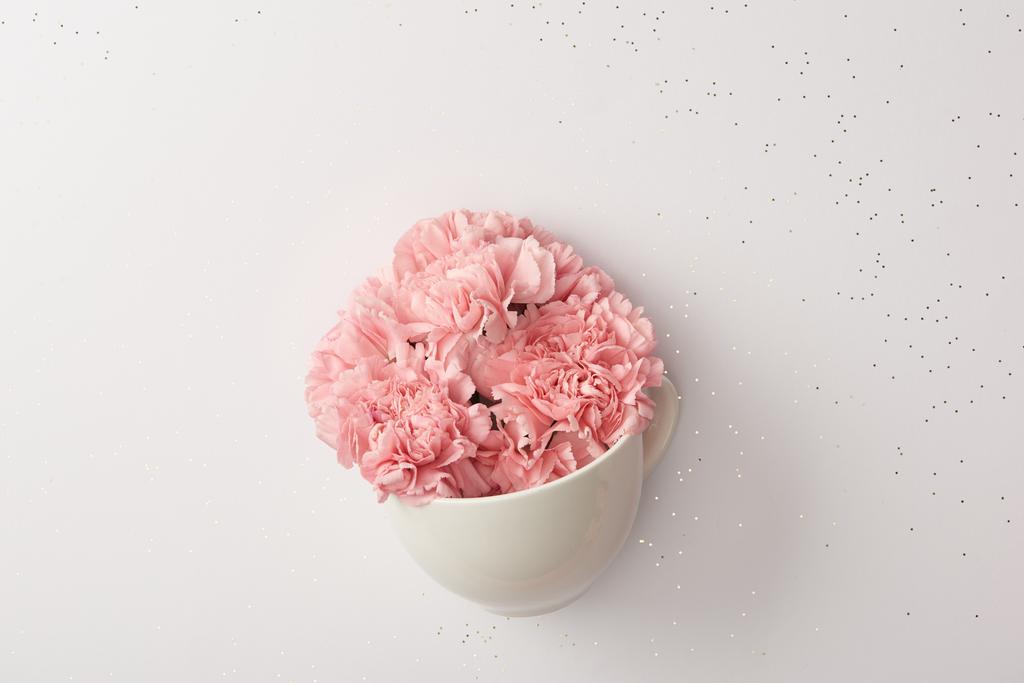 Piękne różowe kwiaty goździków w białe filiżanka na szarym tle - Zdjęcie, obraz