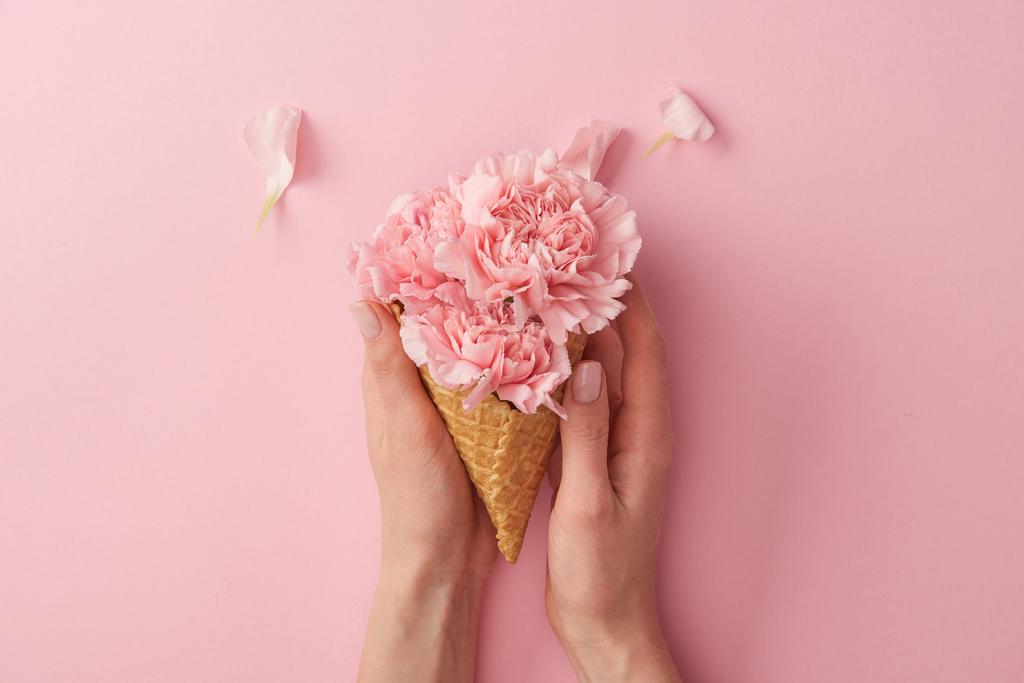 cropped shot of woman holding wafer cone with beautiful tender flowers isolated on pink  - Photo, Image