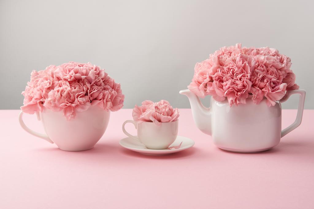 tazze bianche e bollitore con bellissimi fiori rosa su grigio
 - Foto, immagini