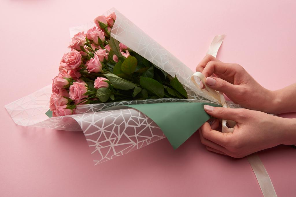 cropped shot of woman wrapping beautiful tender roses on pink - Photo, Image