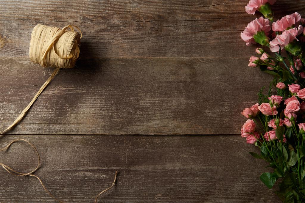 сверху вид красивых нежных розовых цветов и ленты на деревянном фоне
 - Фото, изображение