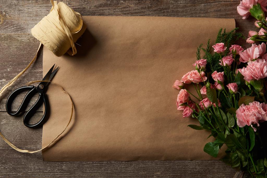 ahşap yüzey üzerinde güzel pembe çiçekler, makas, şerit ve craft kağıt üstten görünüm - Fotoğraf, Görsel