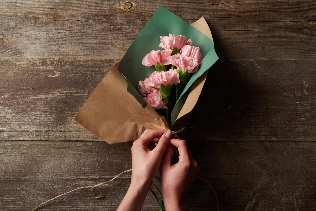 przycięte strzał kobiety Zawijanie różowy Goździk kwiat w paper craft na powierzchni drewnianych - Zdjęcie, obraz